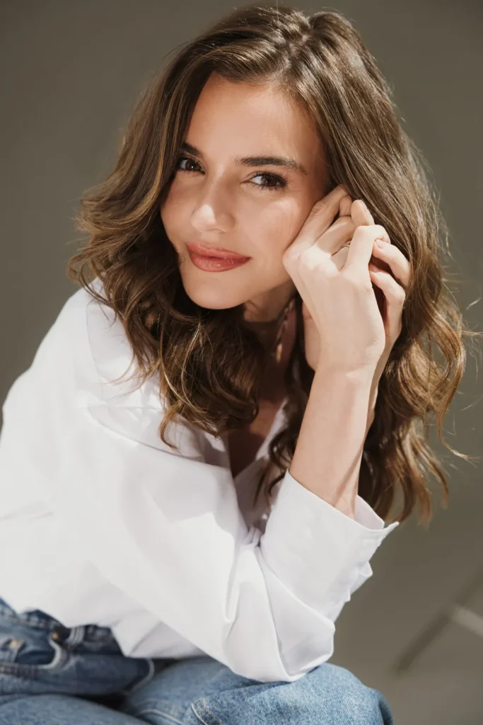 Dra. Joana Webber sorrindo, com a mão no rosto