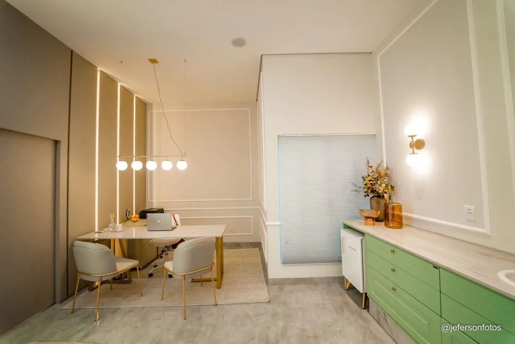 Consultório com mesa, luminária e armários em verde-sálvia